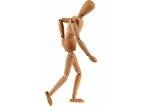 A wooden doll used to show human mobility depicts a person walking with pain in the hip