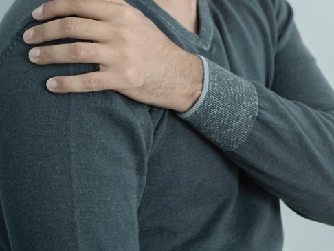 A man holds a sore right shoulder